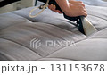 Cleaner hands using vacuum cleaner to meticulously clean sofa from stains dust. 131153678