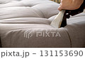 Hand of cleaning service worker removing dirt from sofa with vacuum cleaner. 131153690