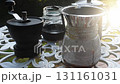 Manual coffee grinder, glass jar, and pour over coffee maker with metal filter on outdoor table 131161031