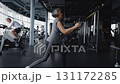 An elderly woman is exercising on a suspension trainer in a gym 131172285