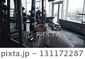 Mature man is lifting heavy dumbbells in a gym setting 131172287