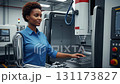 An African woman uses her sleek bionic arm prosthesis to skillfully control a CNC machine in a clean and bright manufacturing environment. The focus is on technology and innovation. 131173827