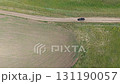 Black pickup truck moving on a dirt road through green and brown fields 131190057
