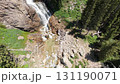 Waterfall cascading down rocky mountainside surrounded by lush green forest 131190071