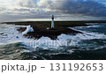 White lighthouse on a rugged rocky coast with crashing ocean waves 131192653