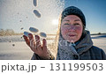 Watch as fine white snow gracefully spirals down from hands, dancing in the light against a bright winter background. Experience the tranquility of a snowy day. 131199503