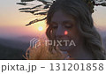Close-up of the face of a young woman with bright makeup and in an autumn headdress against the background of the setting sun in the mountains 131201858