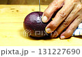 A man cutting ripe sweet passion fruit on wooden cutting board. 131227690