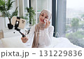 Muslim woman in loungewear using cotton pads and skincare products while recording self-care blog in her modern, bright home interior. Captures contemporary beauty routine and home lifestyle. 131229836