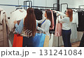 Group of women with shopping bags choosing clothes on hangers in fashion store, enjoying retail shopping and modern lifestyle 131241084
