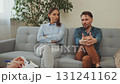 Couple in counseling session, woman crossing arms looking away while man sits thoughtful, showing conflict and tension 131241162