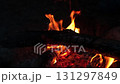 Logs burn brightly in a campfire, casting an inviting glow and warmth during a serene evening in the forest. 131297849