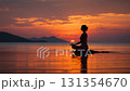 Woman meditating in lotus pose on the sea at sunset 131354670