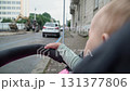 A baby with short hair in a green sweater sits in a stroller and watches attentively and intently the work of a construction excavator on the other side of the road on a cloudy summer day...... 131377806