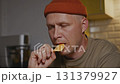 Man eating chip in relaxed moment of evening kitchen ritual 131379927