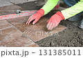 4K Worker placing ceramic floor tiles on a surface with adhesive mortar 131385011