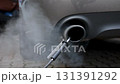 Car exhaust pipe emits dense smoke during emission test on city pavement. Pollution control device measures harmful gases. Service car center garage workshop.  Automobile repair check up diagnosis 131391292