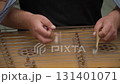 A musician in a black T-shirt professionally and masterfully plays the cymbals with sticks, quickly tapping the strings, a traditional folk ancient musical instrument 131401071