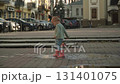 cute baby in pink boots plays with colorful windmill in puddle, runs fast and splashes, waves hands, laughs happily. day, summer 131401075