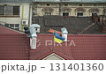 A blue and yellow Ukrainian flag flutters wind skull-like roof building old part city, with broken ancient architectural windows and verandas behind it, building in disrepair. Ivano-Frankivsk 131401360