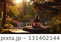 Back view of a woman is trying to meditate on a rock in the park 131402144