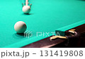 Close-up of a white billiard ball being hit with a cue and falling into the corner pocket of a green table 131419808