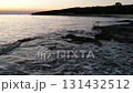 Gentle sea waves hitting rocky shore at sunset with pastel sky and silhouette of trees. Peaceful coastal scene perfect for travel, nature, and relaxation themes. Istria, Croatia. 131432512