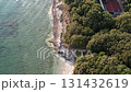 Aerial drone view of a rocky sunset coastline Lanterna peninsula in Istria, Croatia, with crystal clear turquoise water, surf waves, stone steps to the shore, and lush green forest above the cliffs. 131432619