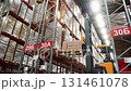 A worker on a forklift lifts boxes of goods and places them on a shelf 131461078
