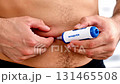 Male individual administering medication using a pen injector on abdomen, showcasing the precise technique and focus in a well-lit indoor setting, emphasizing health management 131465508