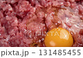Fresh chicken egg yolk falling on minced pork meat in slow motion close up. Cooking traditional cutlets. Rotation 131485455