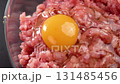 Fresh chicken egg yolk on a minced pork meat in kitchen glass bowl. Cooking traditional cutlets. Rotation 131485456