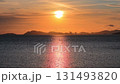 The sun is setting over the ocean. The water is calm and the sky is orange. There are no people or buildings visible in the scene 131493820