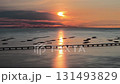 The sun is setting over the ocean. The water is calm and the sky is orange. There are many boats in the water 131493829