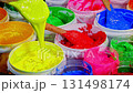 scoop yellow color ink  in white barrel Buckets of thick, colorful paint in vibrant shades of blue, red, green, and yellow, symbolizing creativity and artistic expression. 131498174