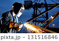 Professional industrial welder creating bright sparks while welding steel beams at construction site during blue hour twilight 131516846
