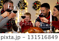 Happy European family toasting with red wine glasses at festive Christmas dinner table with roasted turkey and holiday decorations 131516849