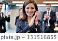 Confident European businesswoman in navy suit receives applause from colleagues in modern corporate office environment 131516855