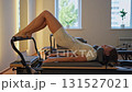 Woman training on the reformer bed at Glute bridge Pilates workout. Reformer pilates studio machine for fitness workouts in gym. Fit, healthy and strong authentical body. Fitness concept 131527021