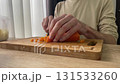 Man slices carrot on a wooden cutting board 131533260