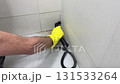 Man wearing protective gloves cleaning the bathroom with steam generator 131533264