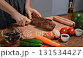Woman preparing snack in kitchen. Cutting black baguette on board with vegetables and eggs. 131534427