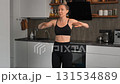 Woman in dark sportswear exercising at home with kitchen background. Home workout in small apartment. 131534889