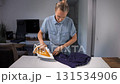 Middle-aged woman ironing a man's shirt in her living room. Domestic chore. 131534906