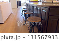 Wide view of kitchen island surrounded by round wood and metal industrial-style bar stools. Scene is naturally lit with hardwood floors. 131567933