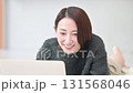 部屋でうつ伏せでスマホをタップするかわいい女性のクローズアップの動画　秋冬のニット 131568046