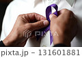 Man hands pinning a purple awareness ribbon onto a white shirt, symbolizing support and solidarity 131601881