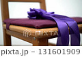 Elegant purple ribbon bow on a wooden chair with a maroon cushion, swaying gently 131601909
