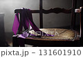 Dramatic close up of a vibrant purple ribbon draped over an old rustic wooden chair 131601910