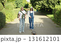 Two friends enjoy a sunny afternoon learning to skateboard on a park pathway 131612101